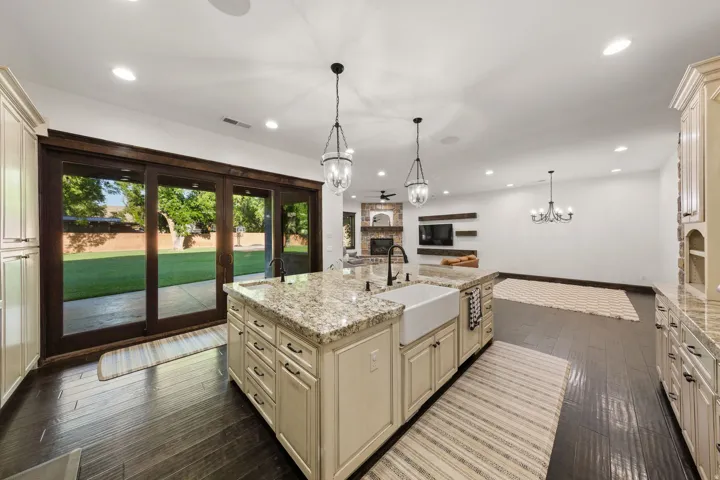 Kitchen island featuring an undermount farmhouse sink, granite countertop, and light-toned cabinetry