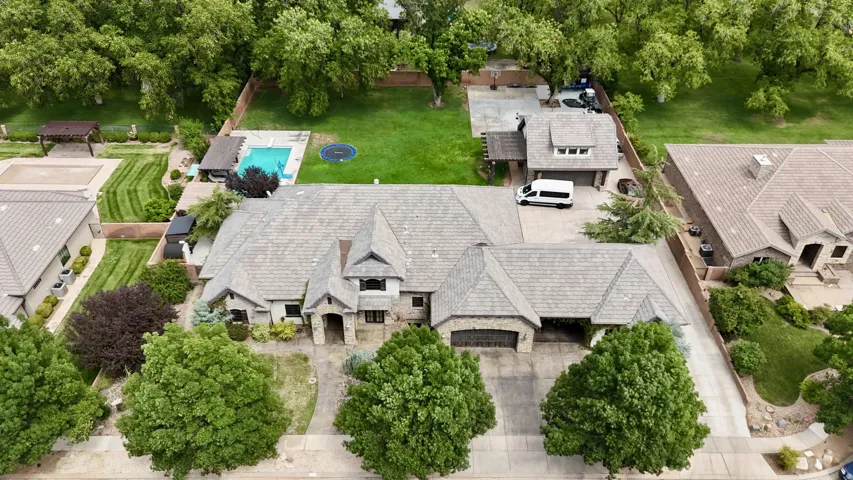 Stone exterior residence with a multi-gabled roofline, attached garage, and surrounding mature trees