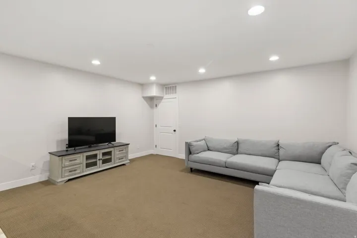 Carpeted living space with recessed lighting and neutral wall tones