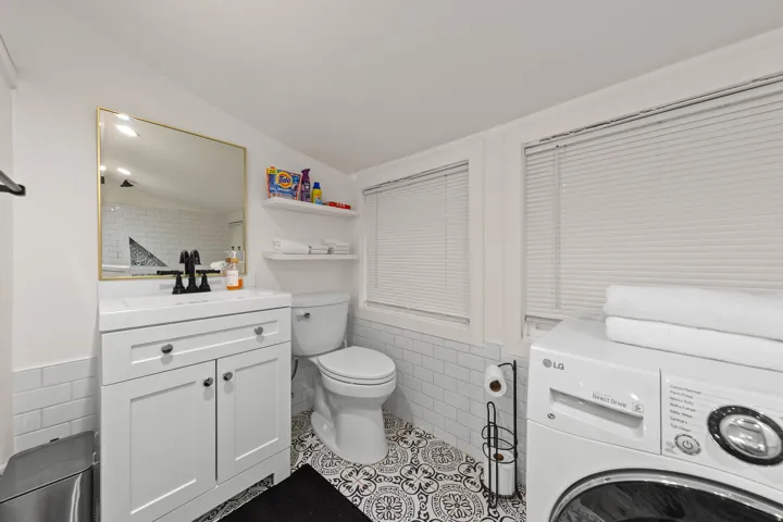 Bathroom featuring a white vanity with integrated sink, black hardware, and a gold-framed mirror
