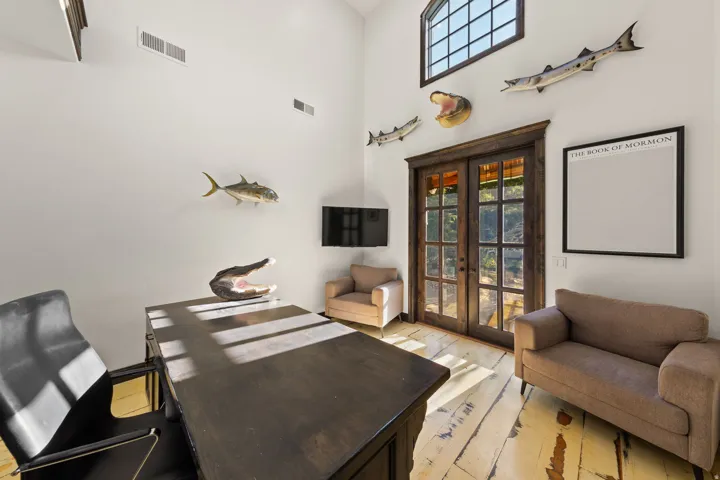 Room featuring a vaulted ceiling, distressed wood-finish flooring, and double French doors with transom window