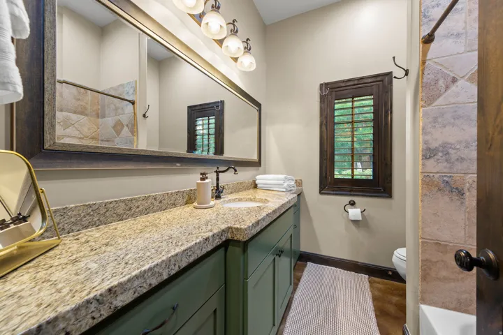Bathroom vanity with granite countertop, integrated sink, and dark green cabinetry
