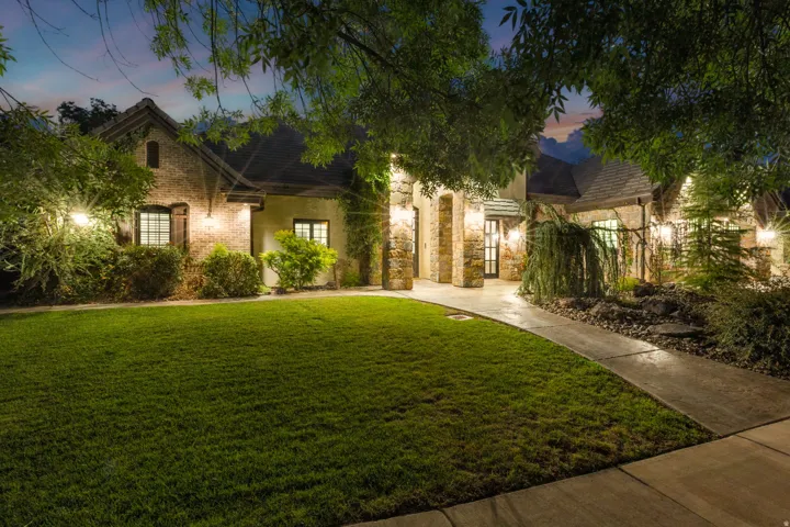Brick and stone facade residence featuring a front lawn and paved walkway