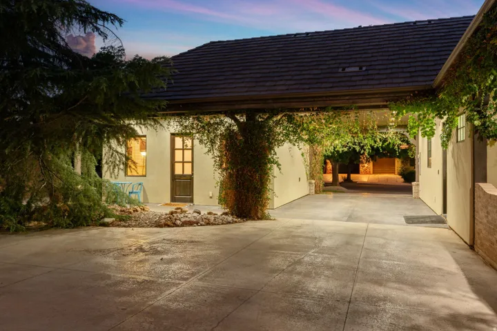 Covered breezeway with mature climbing vines and a concrete driveway