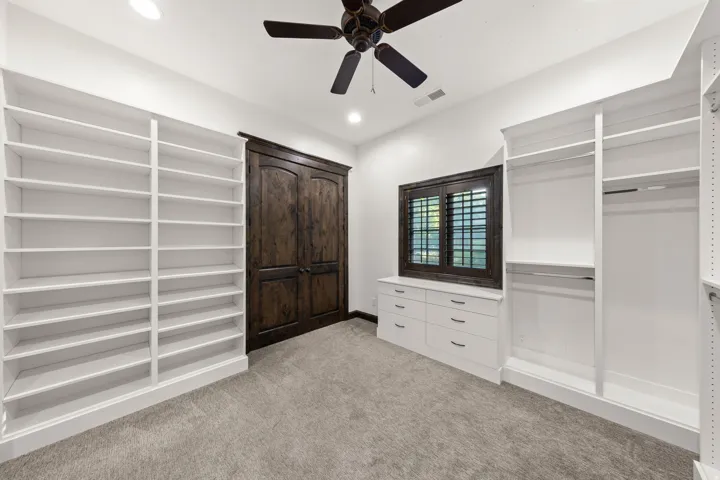 Room featuring recessed lighting, a ceiling fan, plush carpeting, built-in shelving, and a built-in dresser with a window