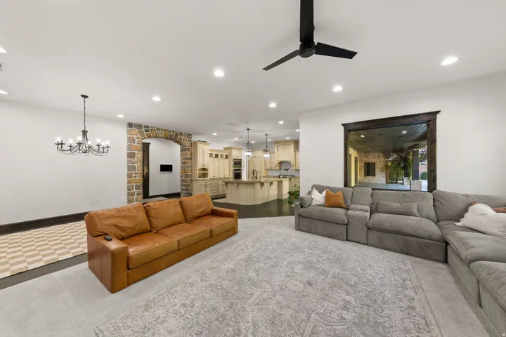 Spacious living area featuring recessed lighting, a black ceiling fan, and a chandelier