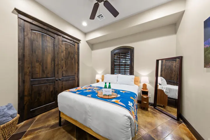 Spacious sleeping area featuring wood-finish flooring, a ceiling fan, recessed lighting, a window with dark wood shutters, and dark wood double closet doors