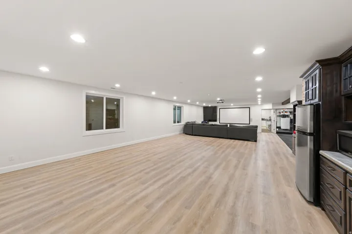 Expansive lower-level entertainment space featuring light wood-finish flooring, recessed lighting, and white walls
