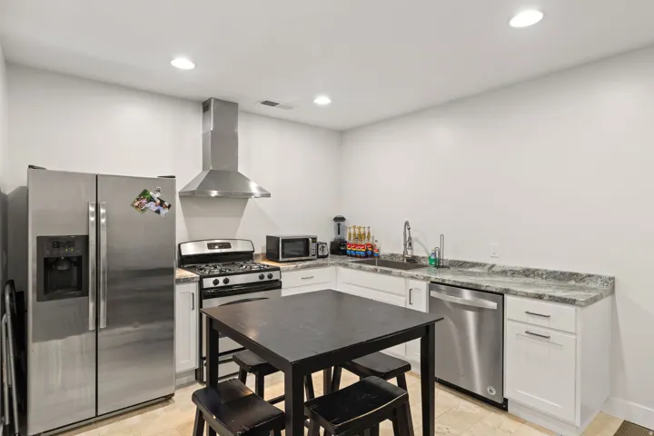 Kitchen featuring stainless steel appliances, white cabinetry, variegated stone countertops, a stainless steel sink, and recessed lighting