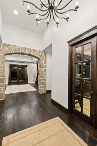 Vaulted entryway featuring a stone archway, wood-finish flooring, recessed lighting, and a wrought iron chandelier