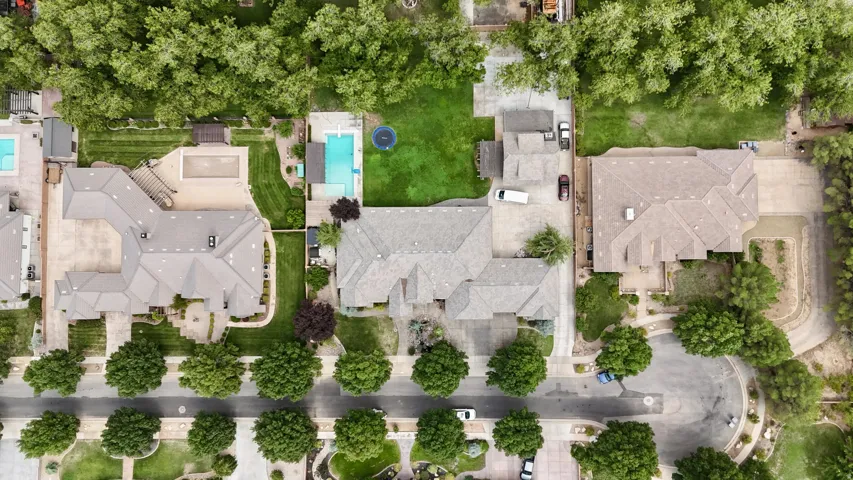 Expansive property featuring a large residence with a multi-gabled roof, extensive paved driveway, and manicured landscaping