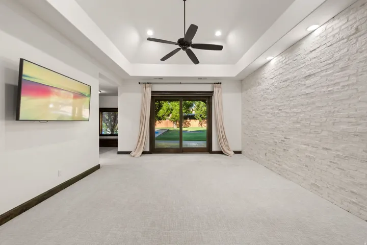 Spacious room featuring a tray ceiling with recessed lighting, a ceiling fan, and light gray wall-to-wall carpeting