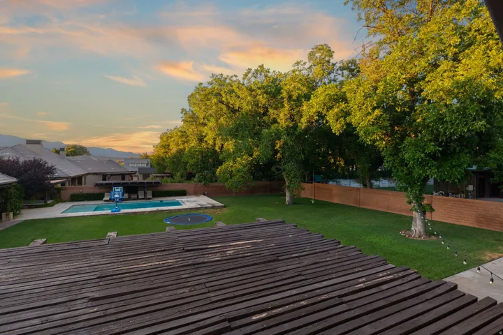 Expansive backyard featuring a large swimming pool, surrounding concrete decking, and a spacious lawn area