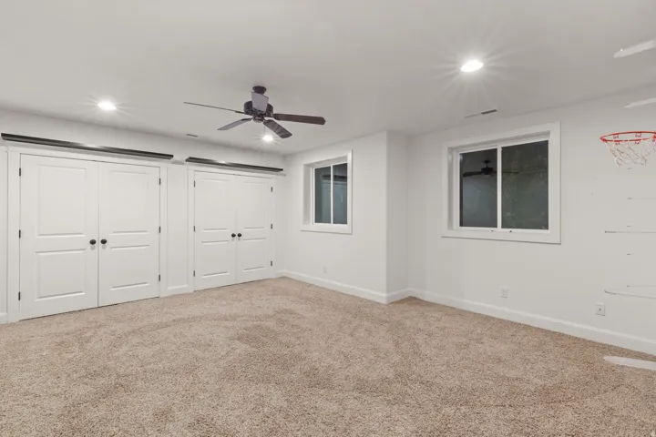 Spacious room featuring neutral carpeting, recessed lighting, and a ceiling fan