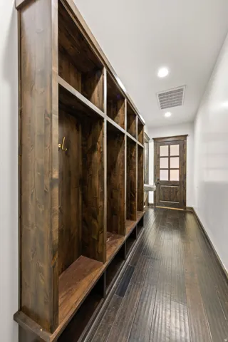 Built-in wooden cubby storage system with integrated hooks and bench seating, set against white walls