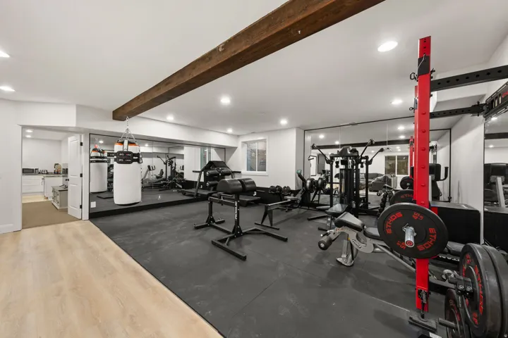 Dedicated fitness area featuring rubber flooring, mirrored walls, and a visible wood beam accent