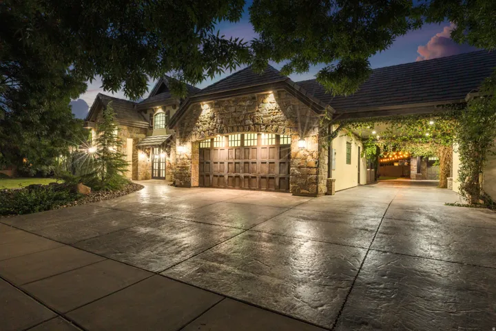 Stone-clad exterior with a multi-gabled roofline, featuring an attached two-car garage with wood-panel doors