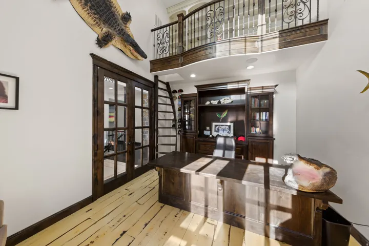 Wood-finish flooring with high ceilings and a built-in dark wood desk and shelving