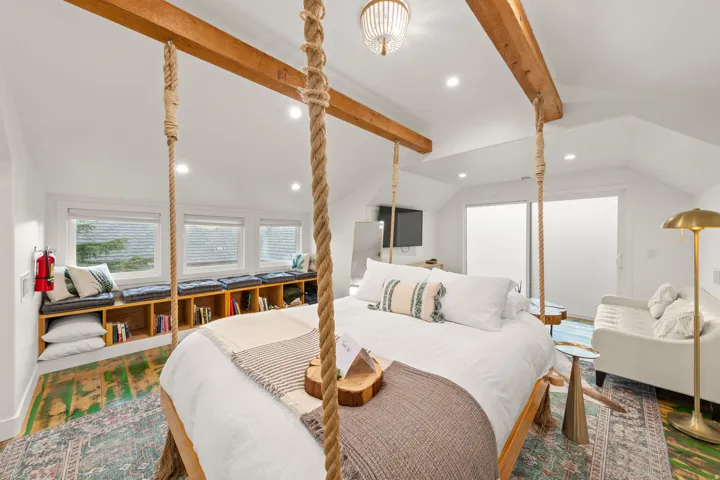 Vaulted ceiling bedroom featuring exposed wood beams and a rope-suspended bed frame