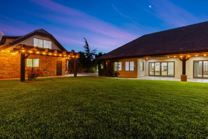 Expansive green lawn with a pergola featuring string lights