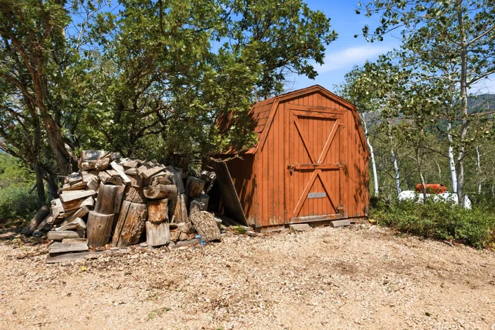 Red gambrel-roof shed with double entry doors and metal hardware