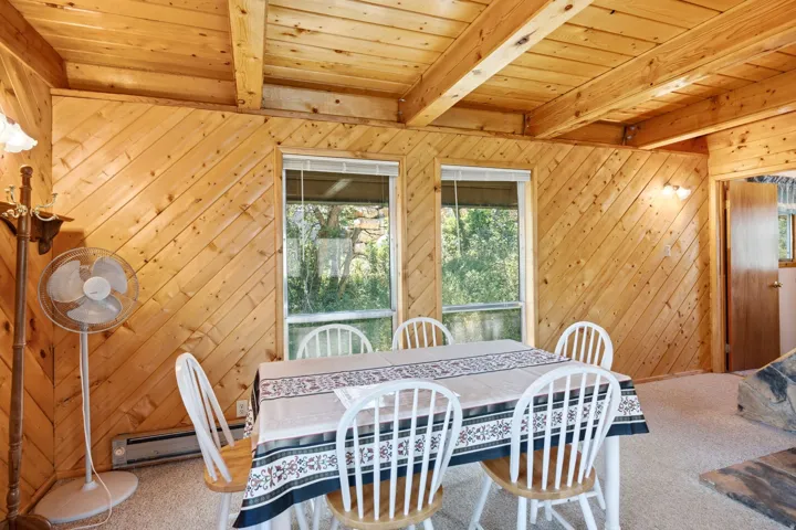 Interior room with wood-finish flooring, diagonal wood paneling, and exposed wood ceiling beams