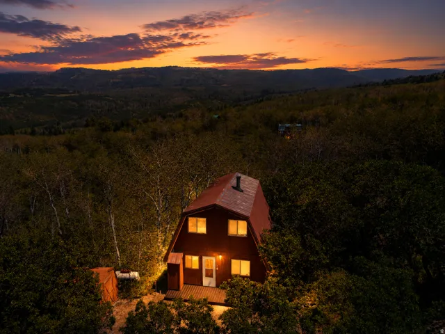 A-frame style home featuring a red exterior, multiple windows, and a front deck