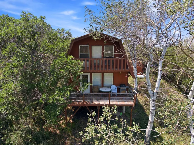 Two-story residence featuring a brown siding exterior, an upper-level balcony, and a ground-level deck with wood railing
