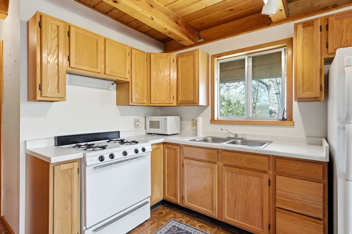 Kitchen featuring wood cabinetry, white countertops, a double basin sink, and a four-burner range