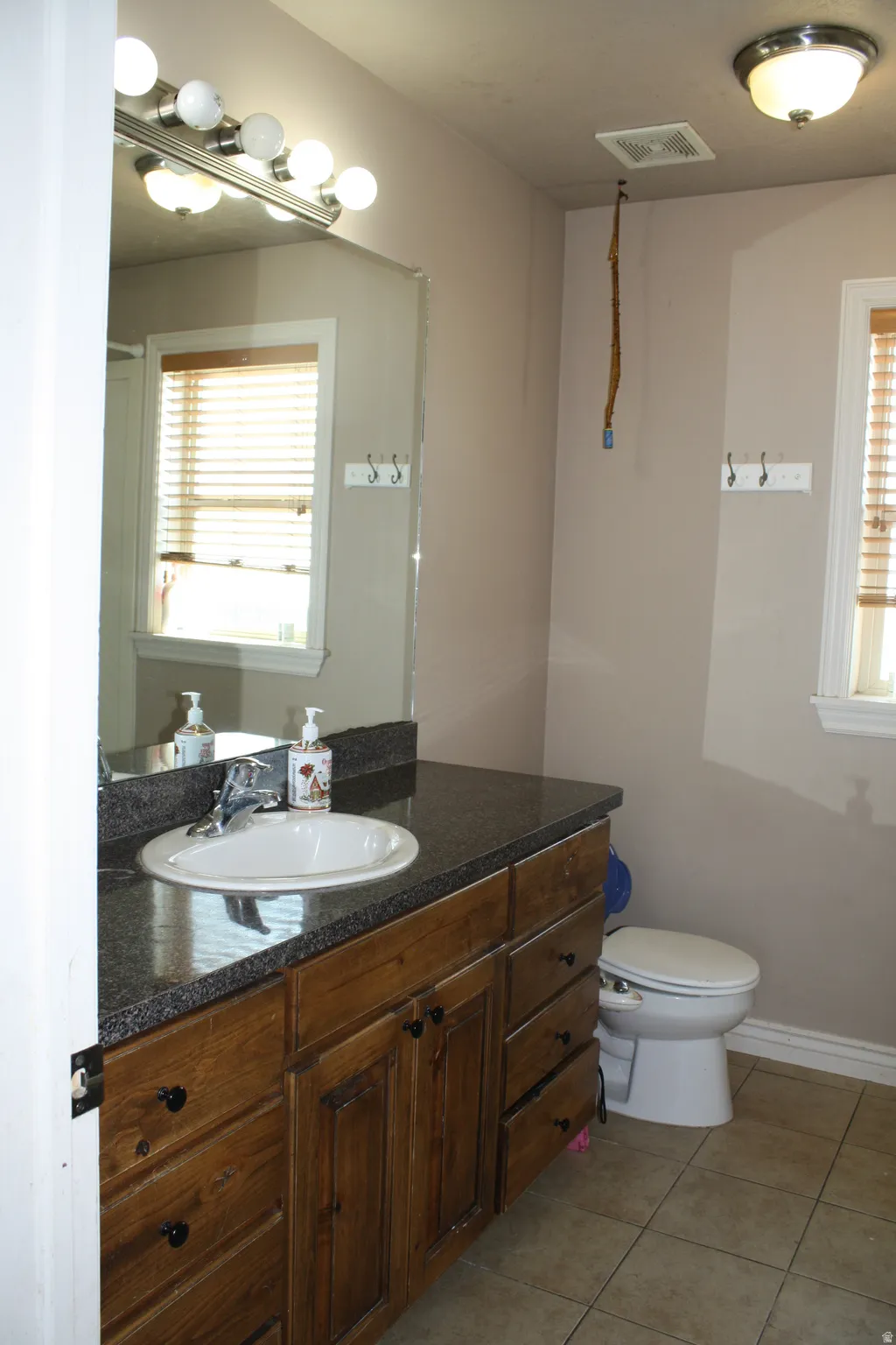 Bathroom vanity featuring a dark wood-finish cabinet with black hardware, an oval undermount sink, and a dark speckled countertop