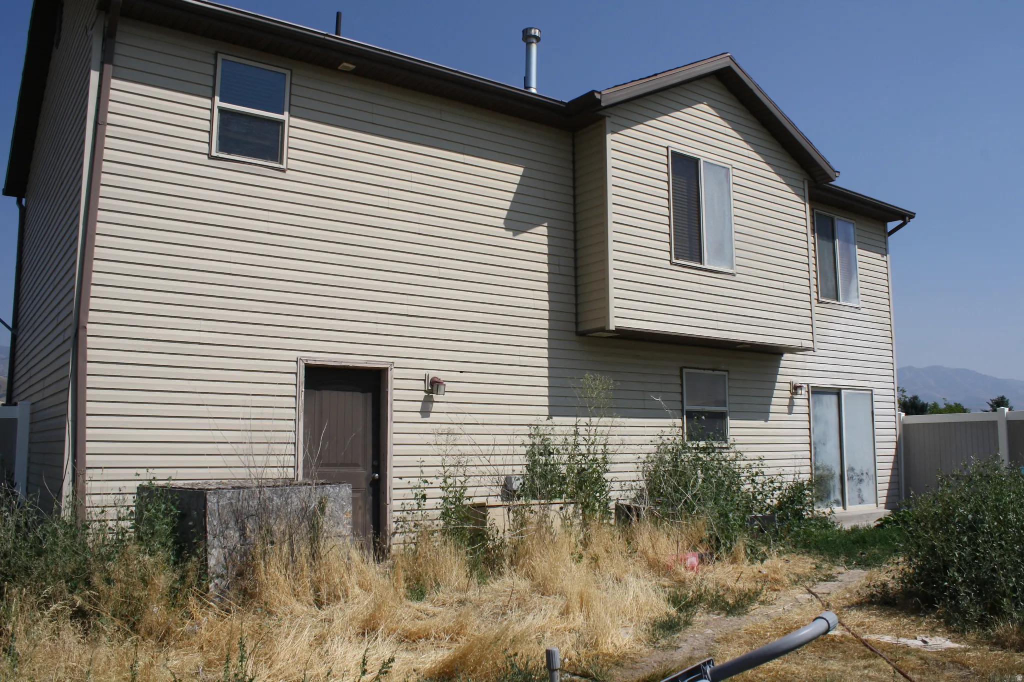 Two-story residence featuring light-colored horizontal siding and a brown roofline