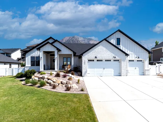 Contemporary white brick and board-and-batten exterior with a dark roof and mountain backdrop