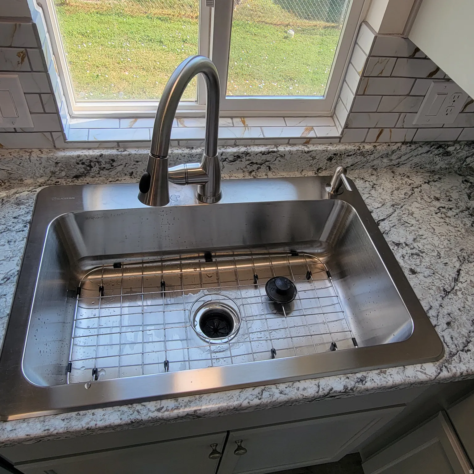 Stainless steel undermount sink with a protective grid, complemented by a brushed nickel pull-down faucet and a coordinating soap dispenser
