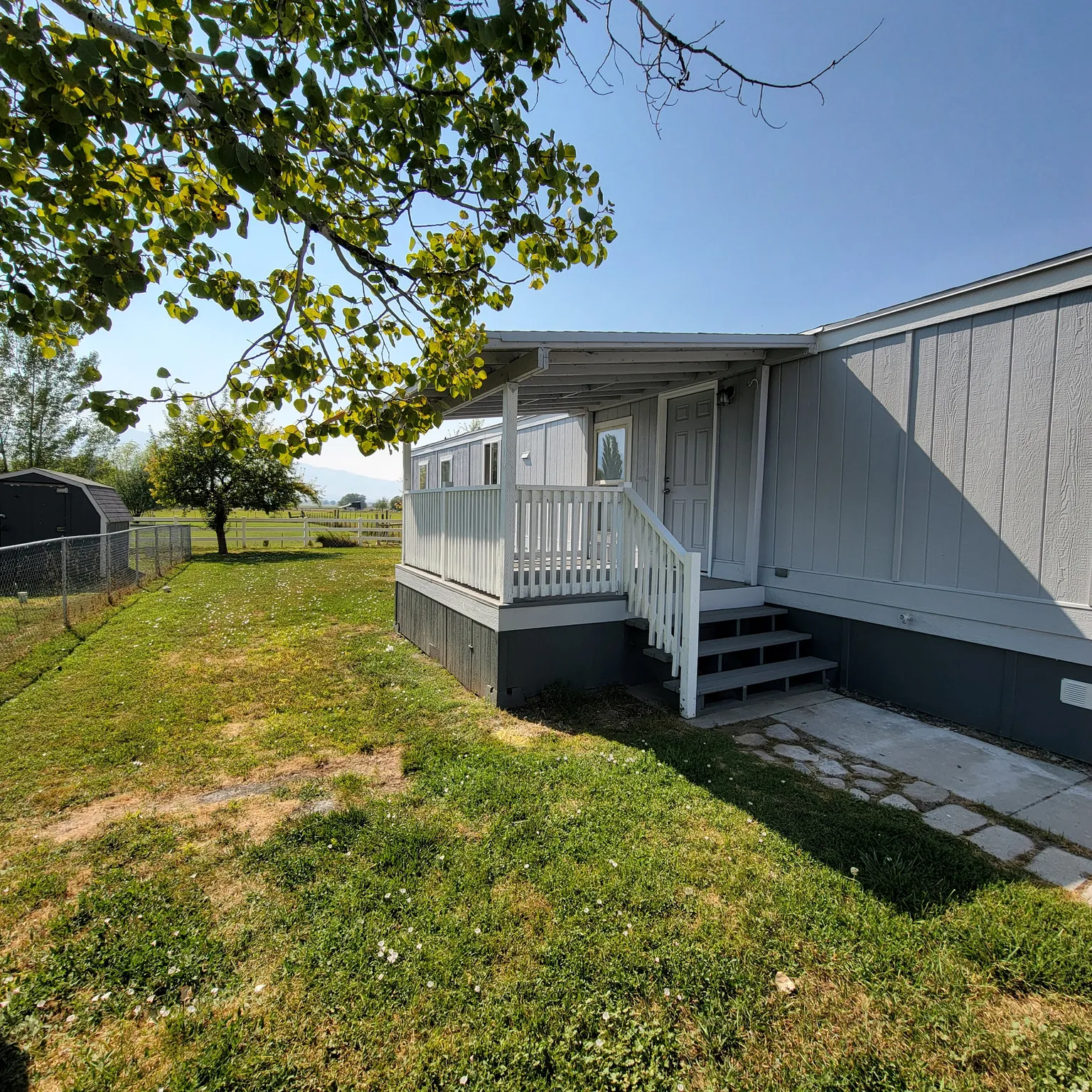 Gray exterior with white trim, featuring a covered porch with white railings and steps