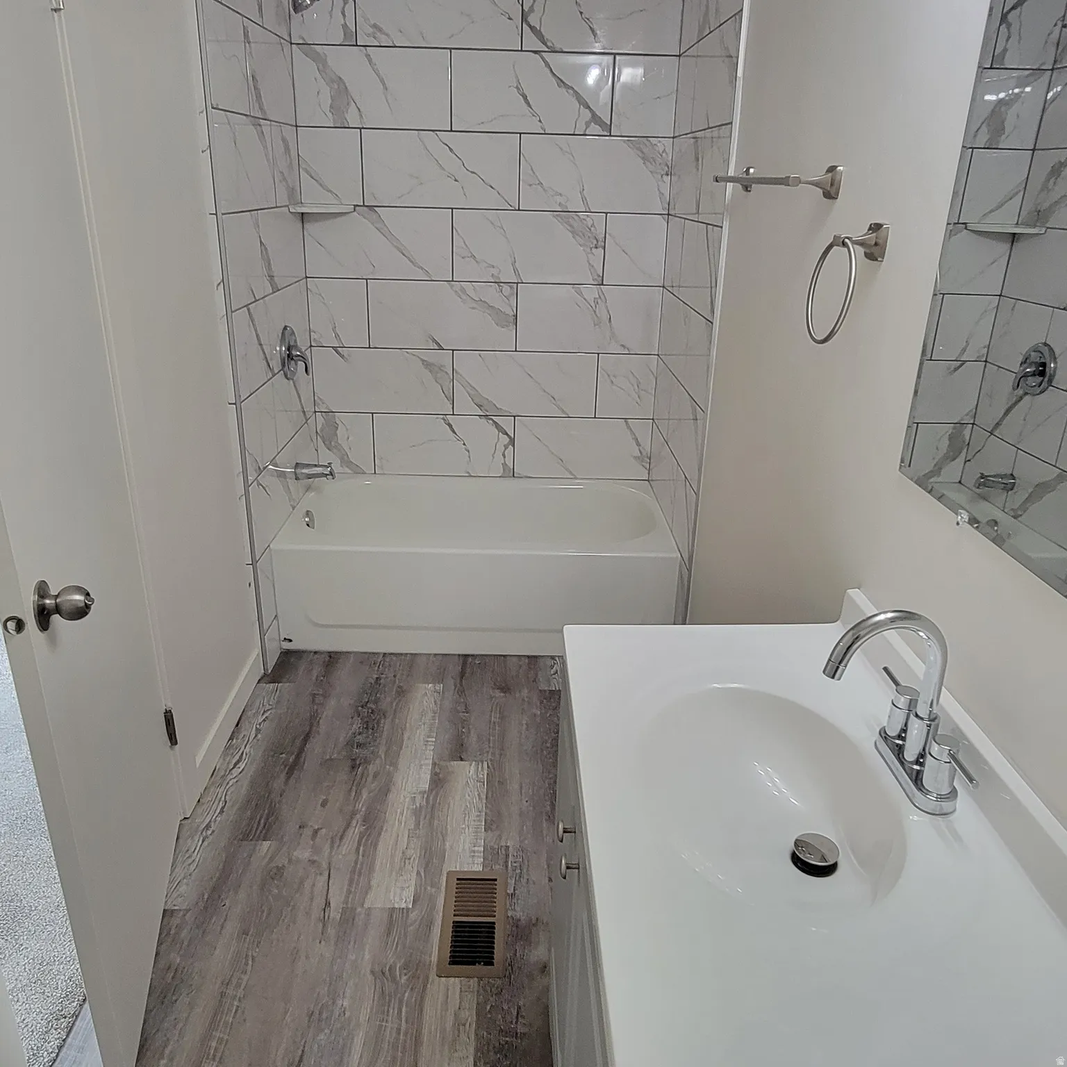 Bathroom featuring a white vanity with integrated sink, chrome faucet, and a large wall-mounted mirror