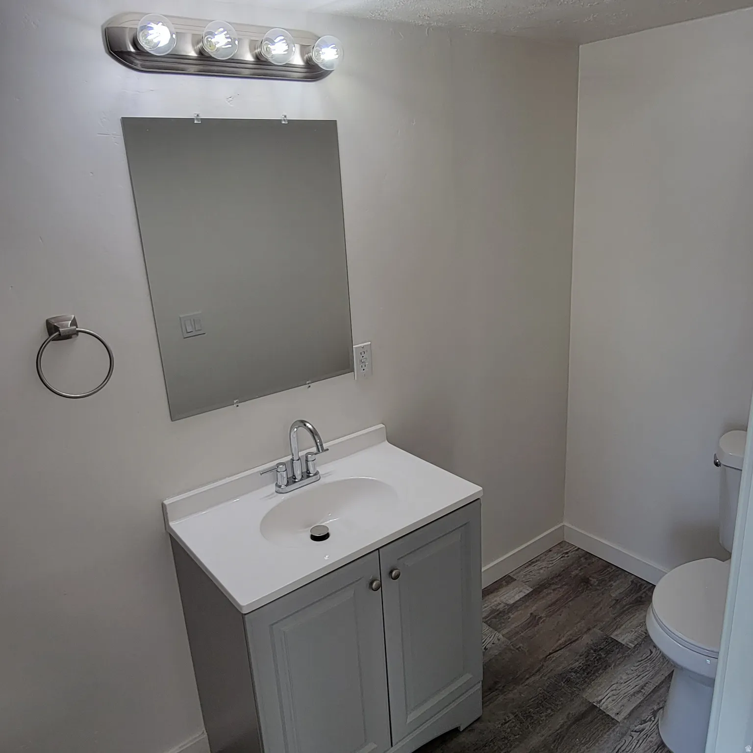 Bathroom vanity with a white countertop and integrated sink, gray double-door cabinetry, and chrome-finish faucet