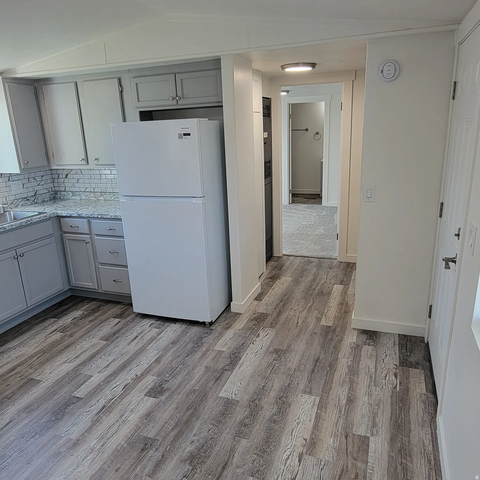 Kitchen featuring wood-finish flooring, light grey cabinetry, and a white subway tile backsplash