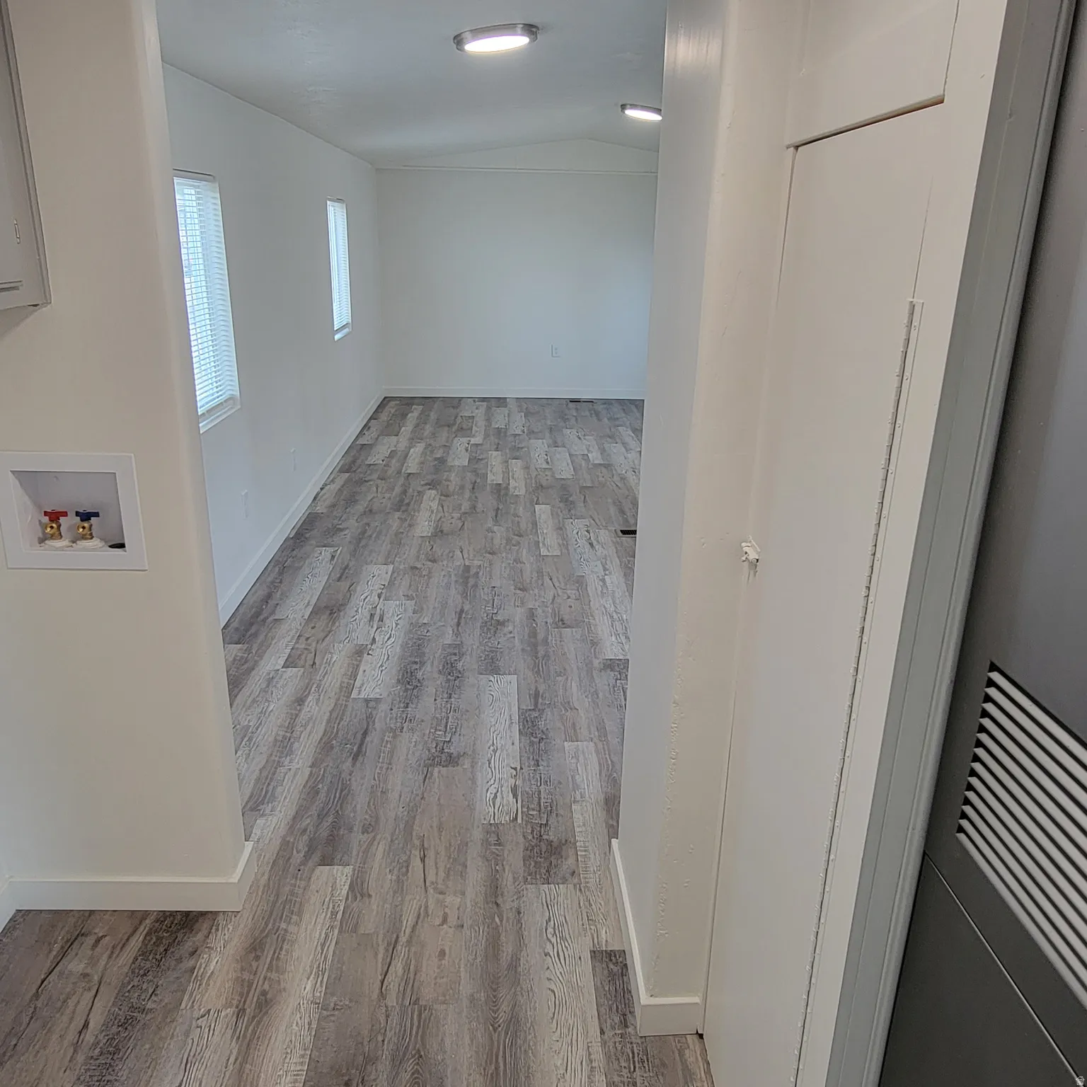 Spacious interior featuring wood-finish flooring, white walls, and contemporary ceiling lighting