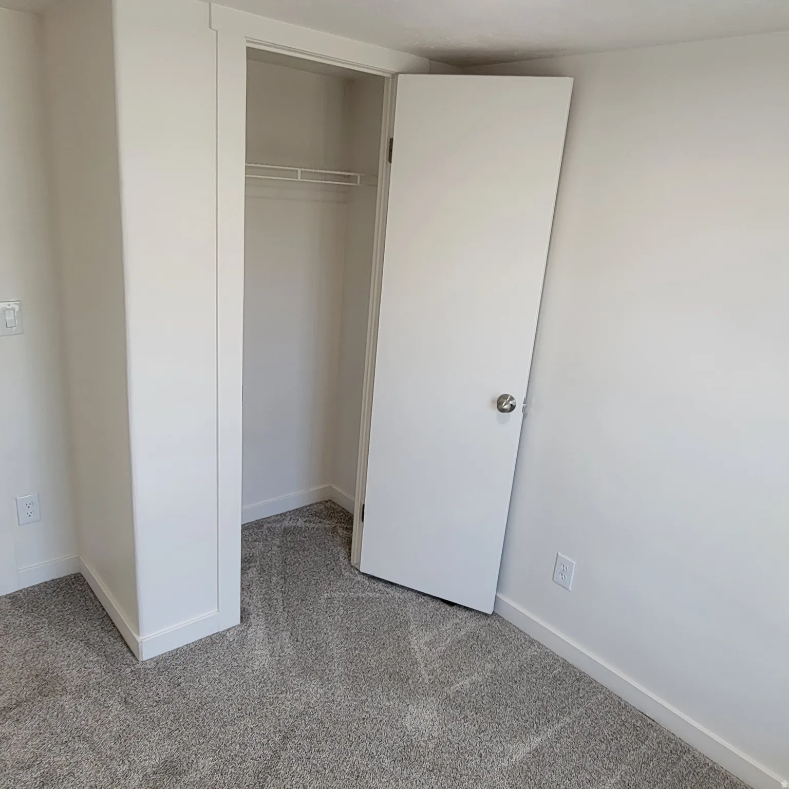 Neutral-toned carpet flooring with white baseboards and trim