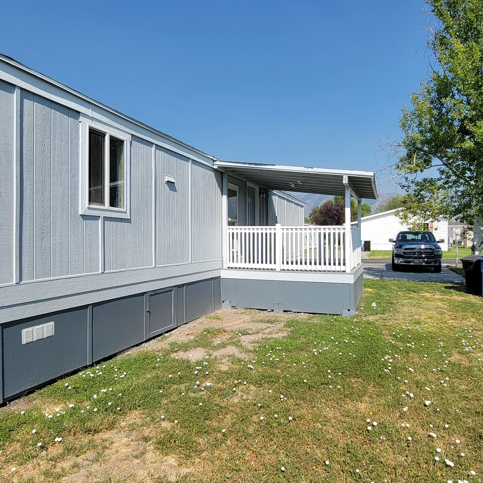 Exterior featuring light blue siding, white trim, and a covered porch with white railings