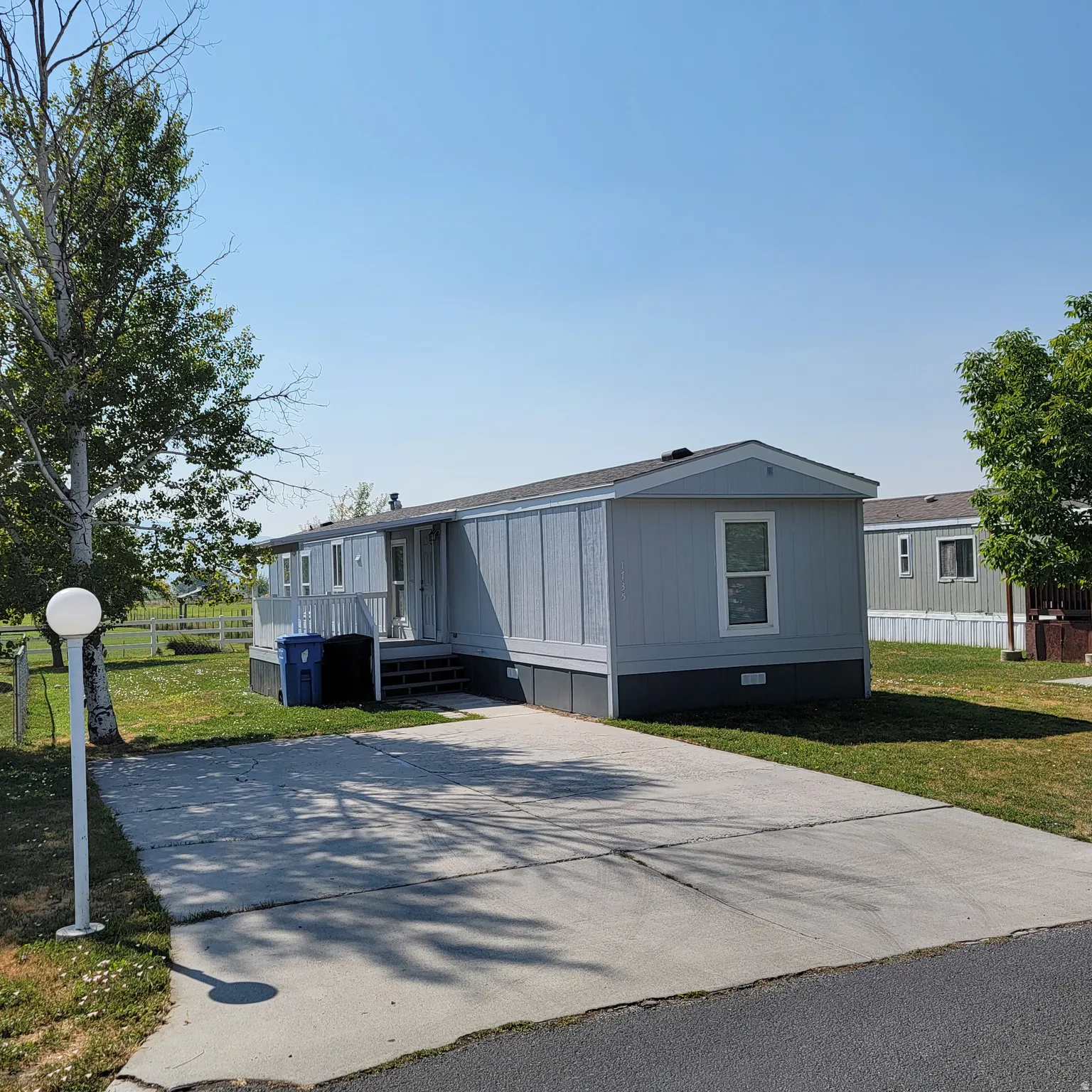 Light blue mobile home with white trim and dark skirting