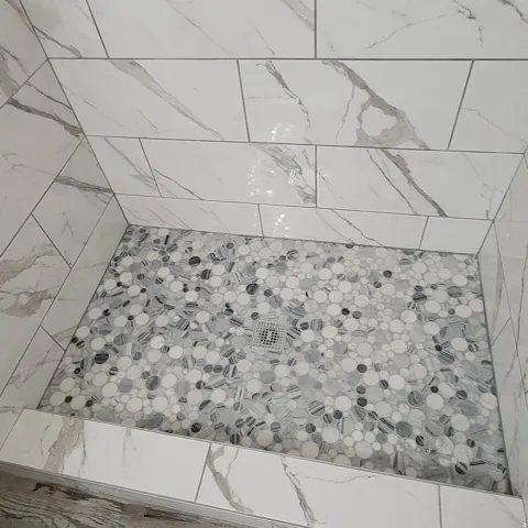 Shower stall featuring large format white tiled walls with grey veining