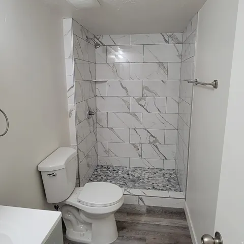 Walk-in shower with marble-look tile surround and mosaic pebble flooring