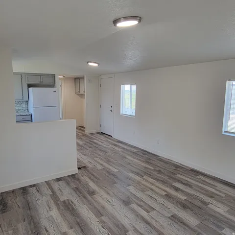 Open-concept living space featuring wood-finish flooring, recessed lighting, white walls, and a partial wall separating the kitchen area