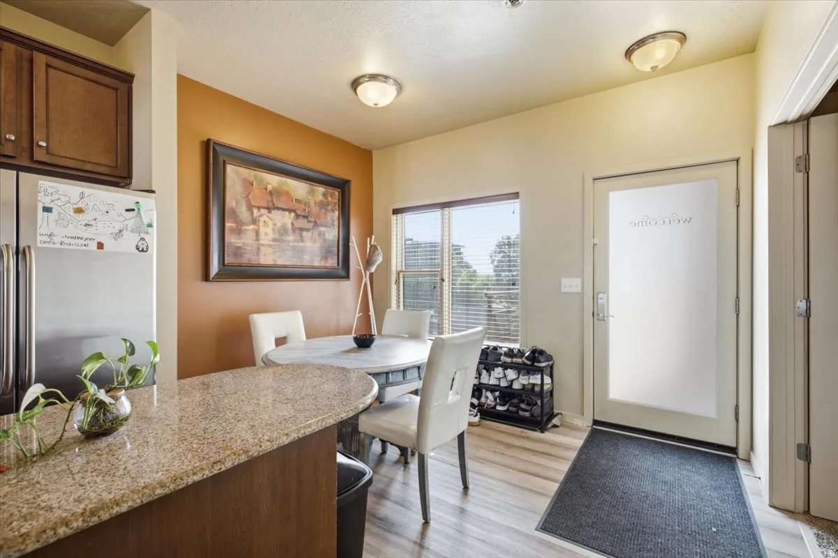 Kitchen and dining area featuring stainless steel appliances, wood-finish flooring, a breakfast bar with a stone-finish countertop, and a dining area with a window