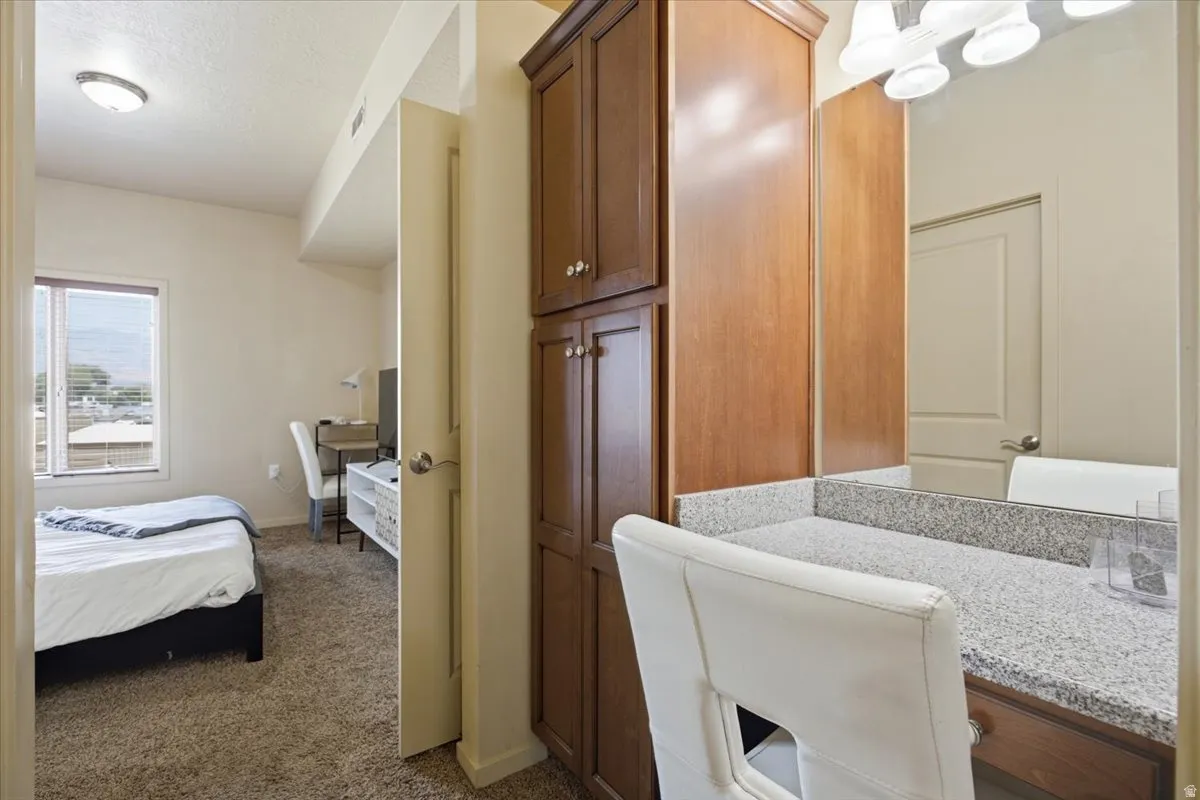 Vanity area featuring a stone countertop, wall-mounted mirror, and integrated lighting