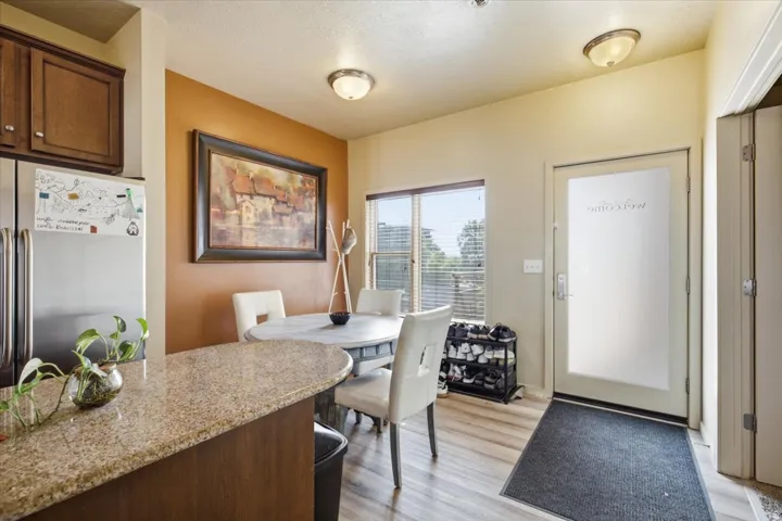 Kitchen and dining area featuring stainless steel appliances, wood-finish flooring, a breakfast bar with a stone-finish countertop, and a dining area with a window