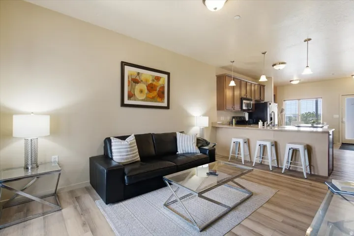 Open-concept living space featuring wood-finish flooring, recessed lighting, and a breakfast bar with pendant lighting