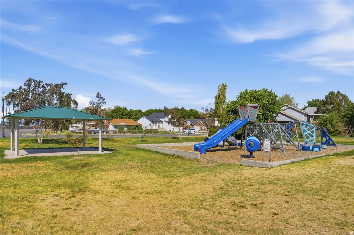 Community park area featuring a playground with slides and climbing structures, a covered picnic area, and open green space