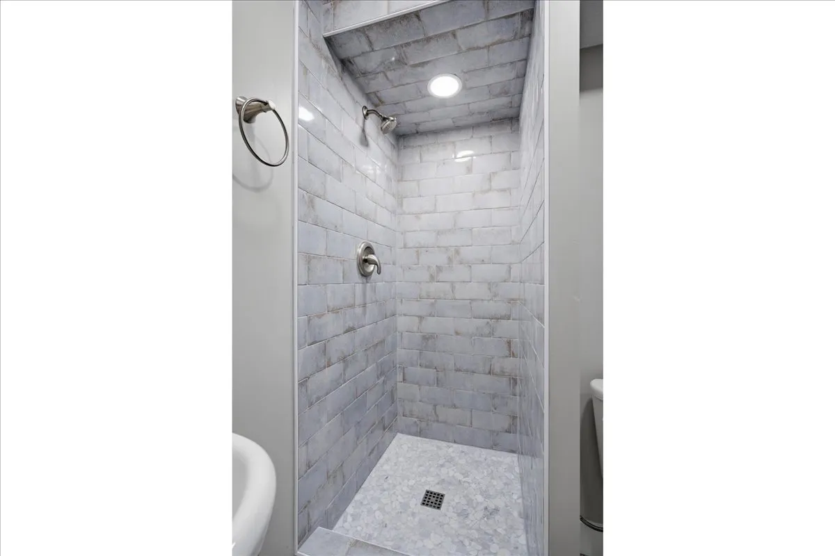 Shower stall featuring subway tile walls, a tiled shower pan, and recessed lighting
